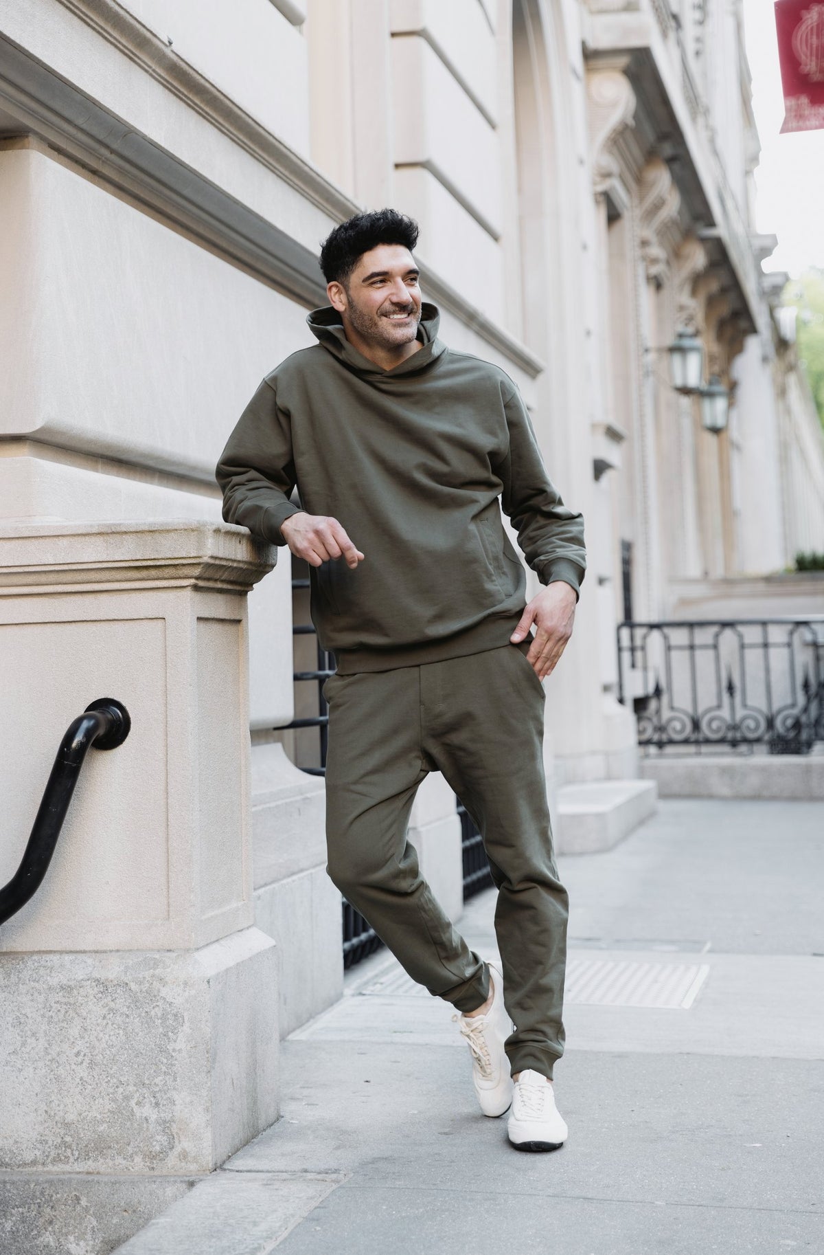 Man in an olive Deccan-Luxe hoodie and jogger set on townhouse steps