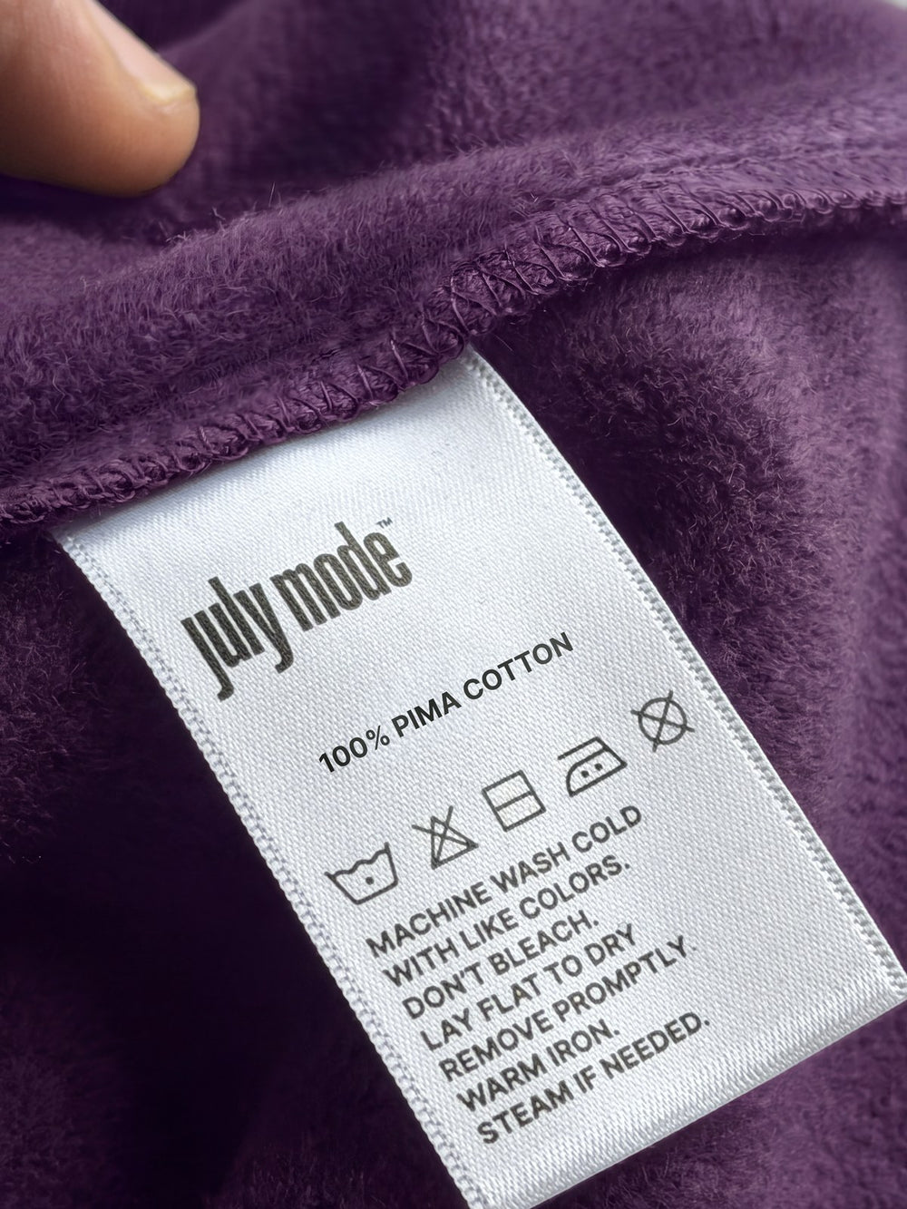 Real July Mode care label on a plum Pima Fleece: 100% Pima cotton