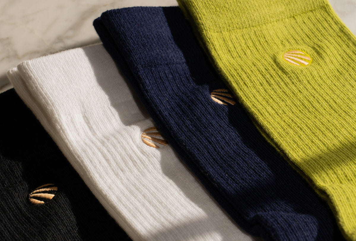 Black, white, navy and lime Organic Cotton Crew Socks laid flat with the sun logo