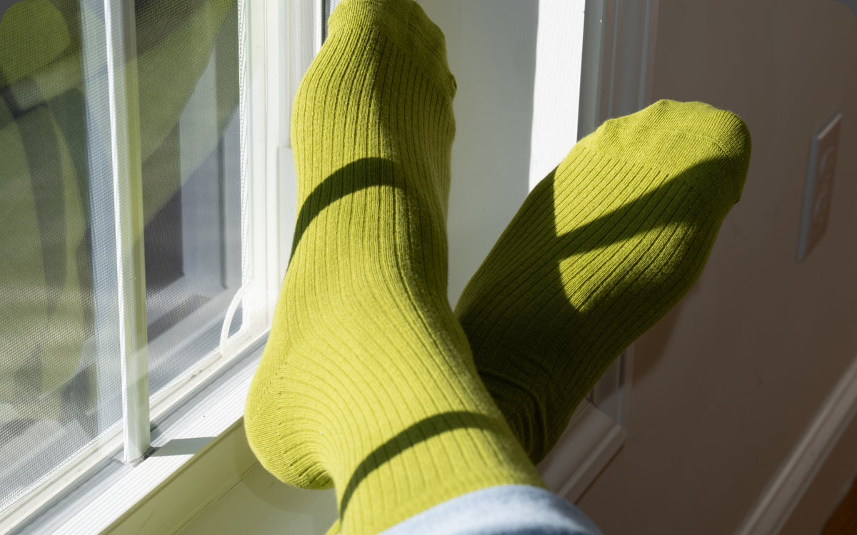 Feet in Pickle green crew socks propped against a sunny window