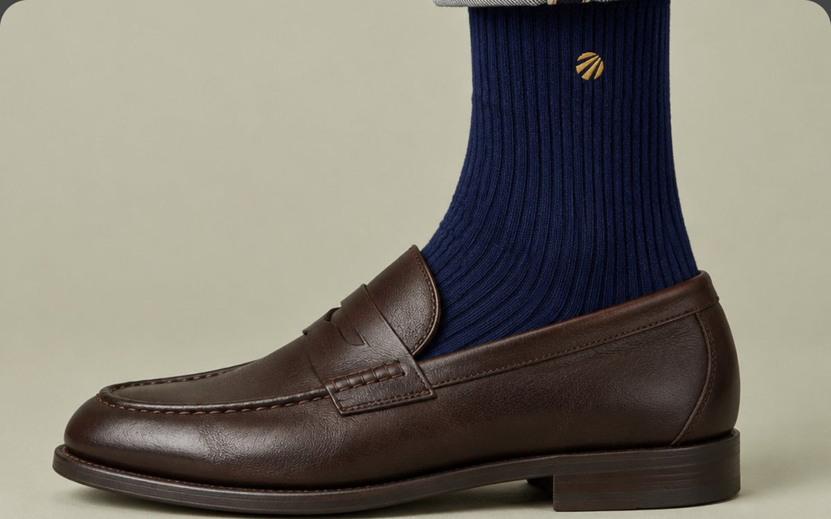 Deep Sea navy crew sock with the gold sun logo, worn with a brown leather loafer