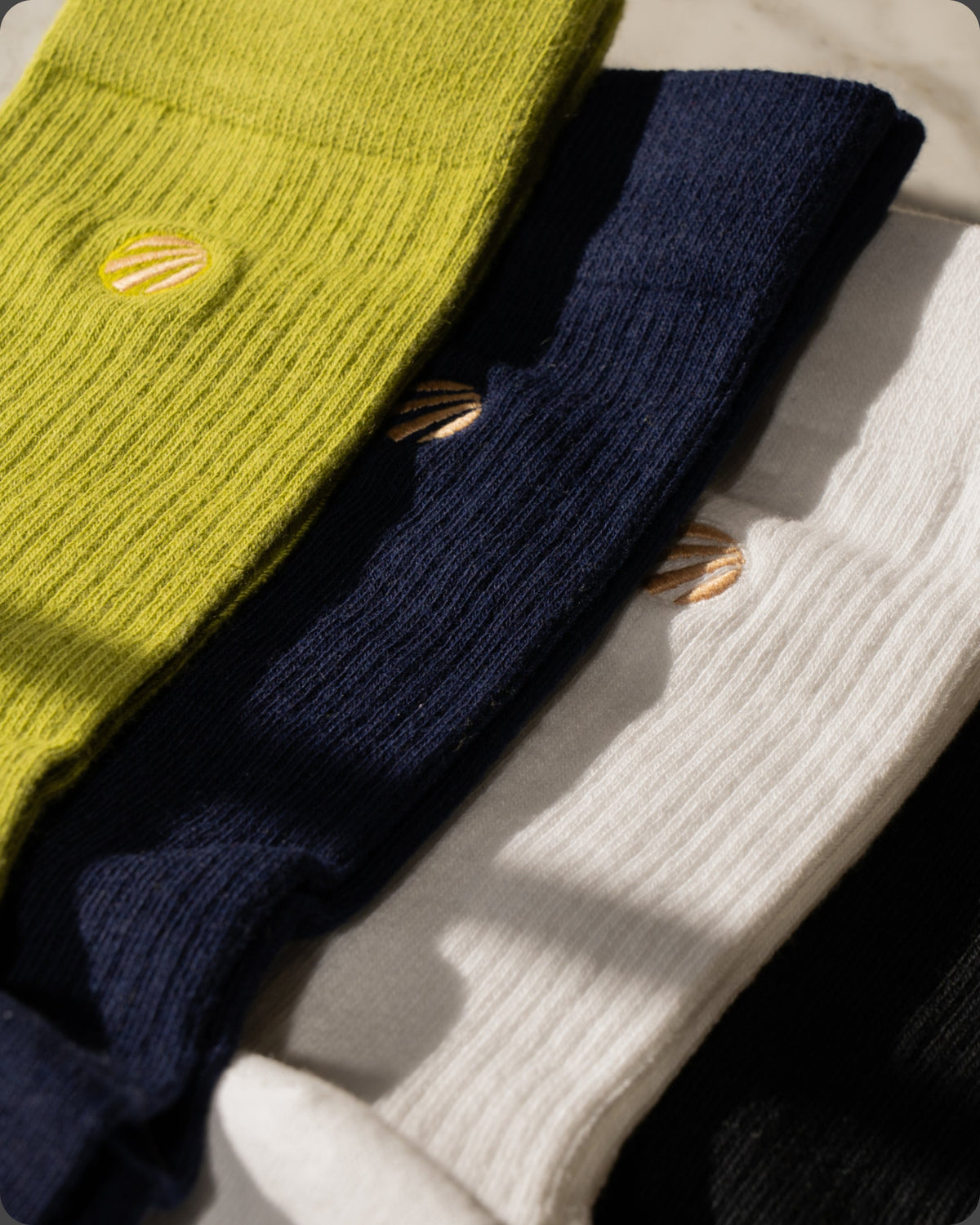 Stack of July Mode organic cotton crew socks in several colors