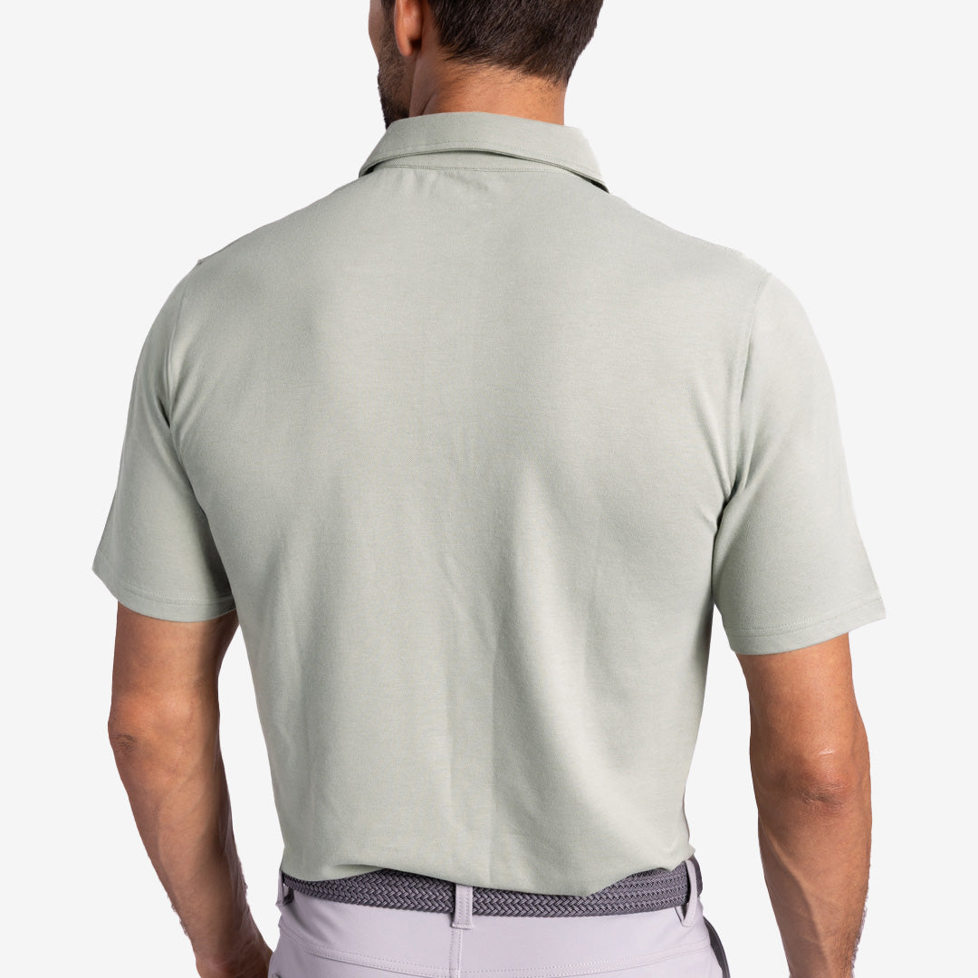Back view of a person wearing a light gray polo shirt and light purple pants on a plain background.