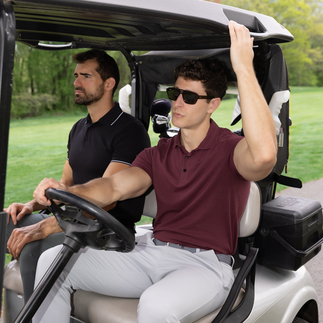 Two men riding in a golf cart on a course.