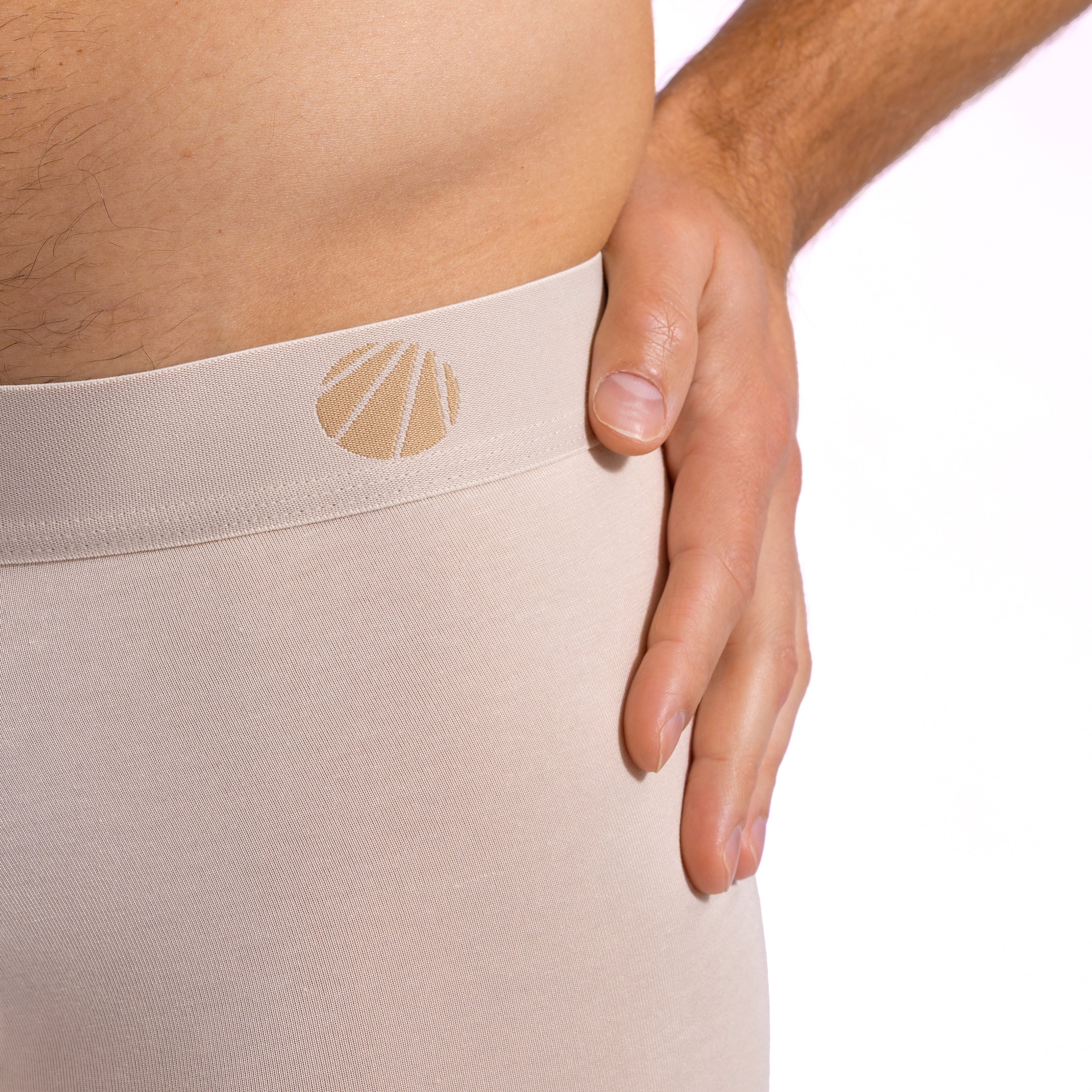 Beige underwear with a logo on the waistband, worn by a person.